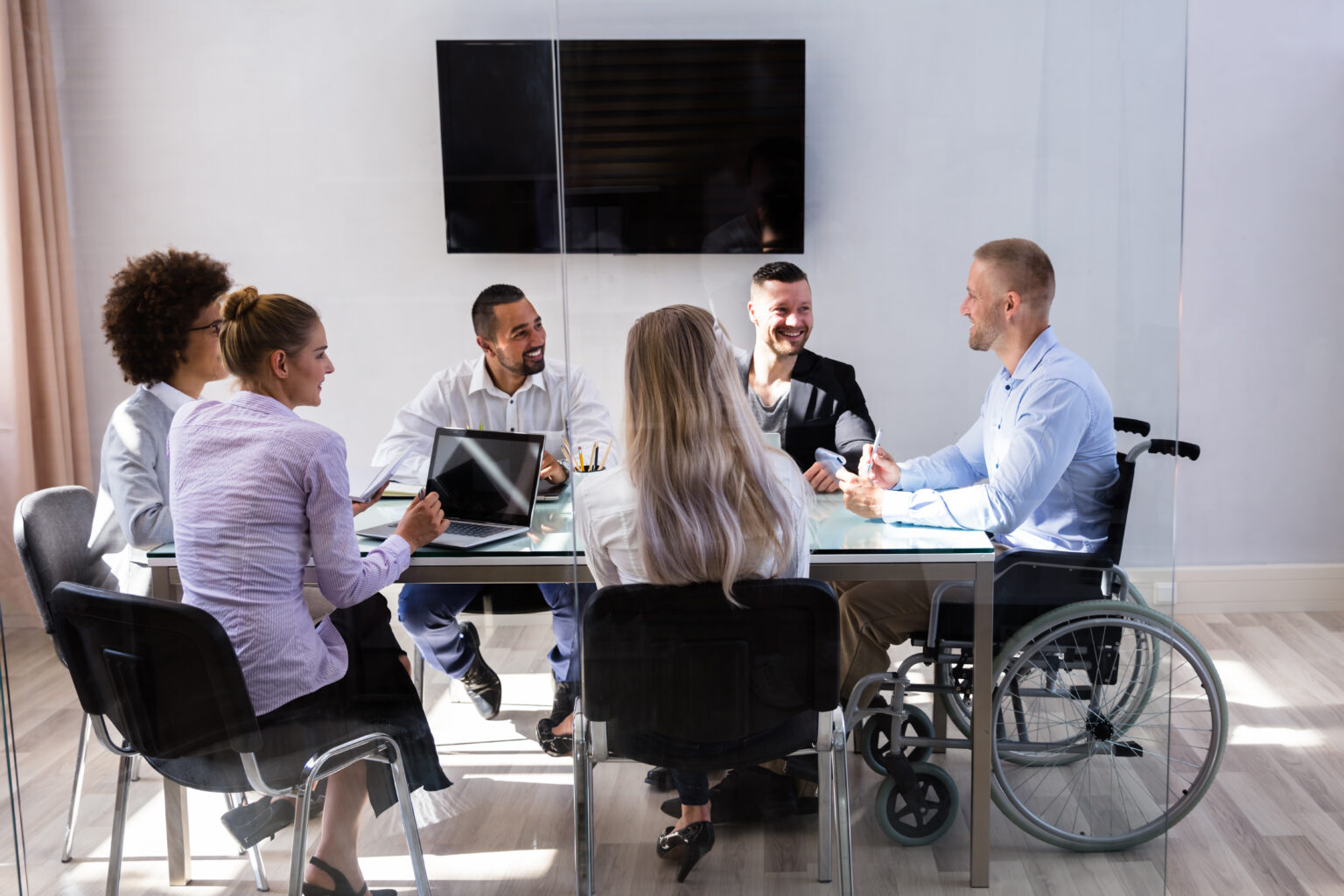 Disabled Male Manager Sitting With His Colleagues At Workplace