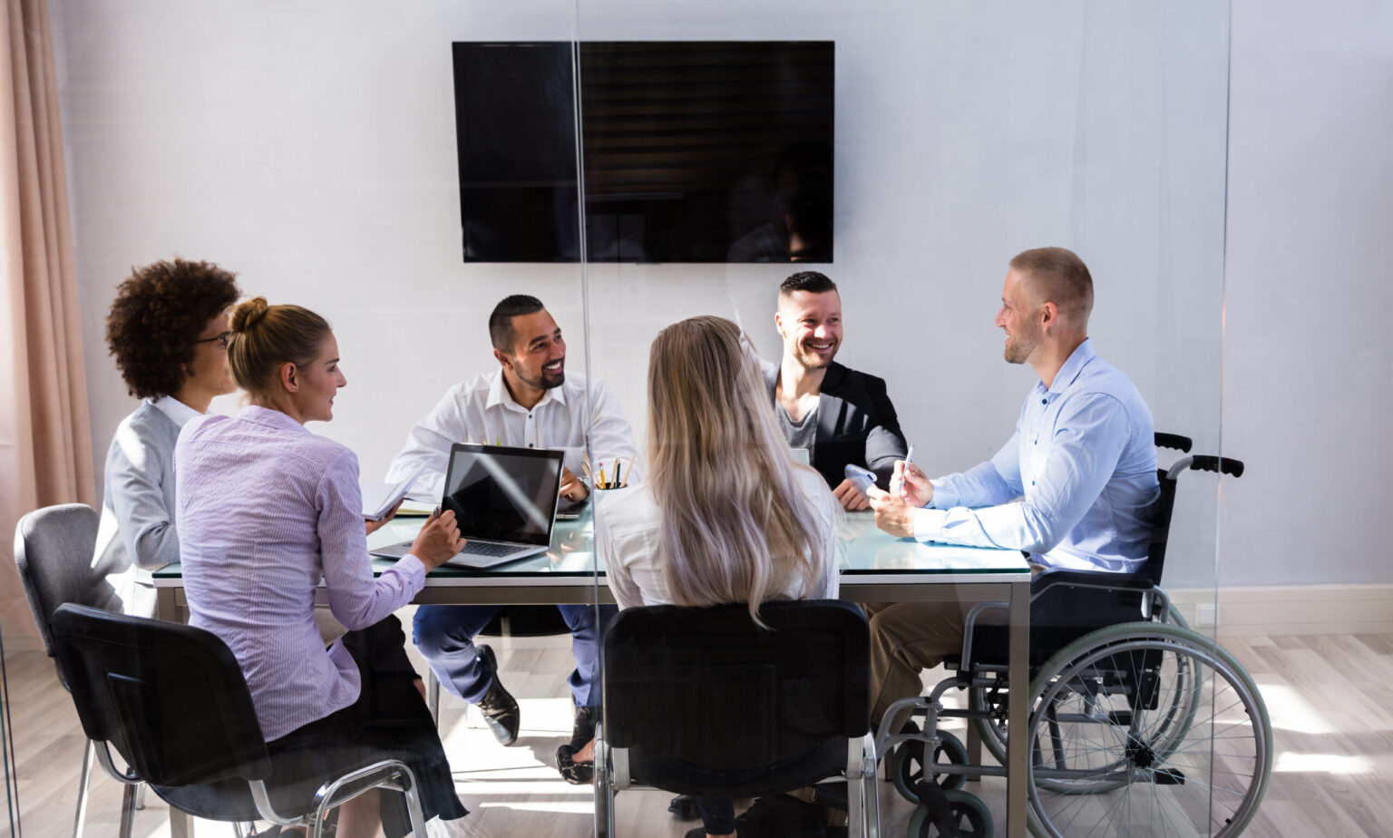 Disabled Male Manager Sitting With His Colleagues At Workplace