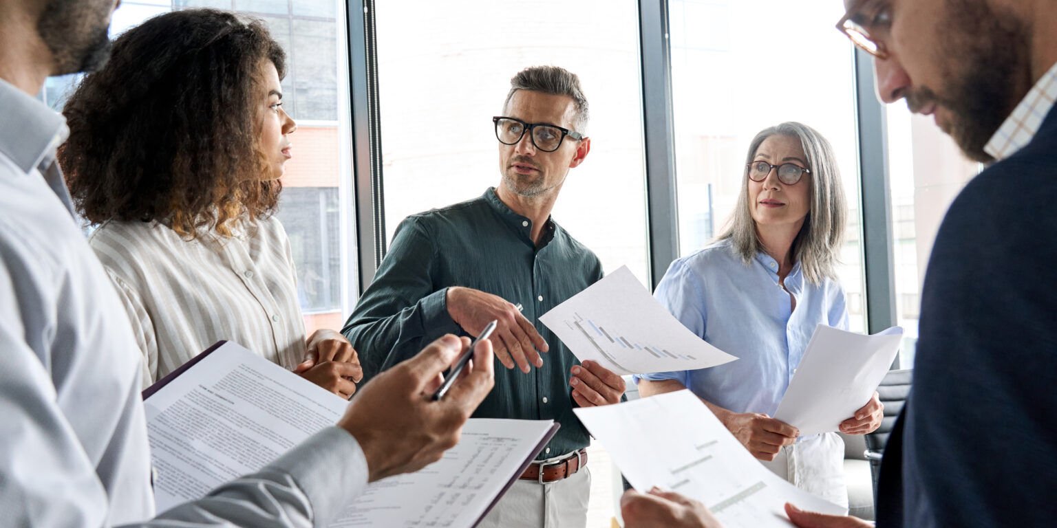 Multiethnic business executive team having discussion at office meeting. Diverse multiracial corporate leaders group brainstorming analyzing project financial result in board room developing strategy.